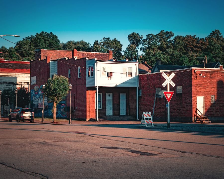 A row of brick storefronts on a quiet small-town street corner, evening light