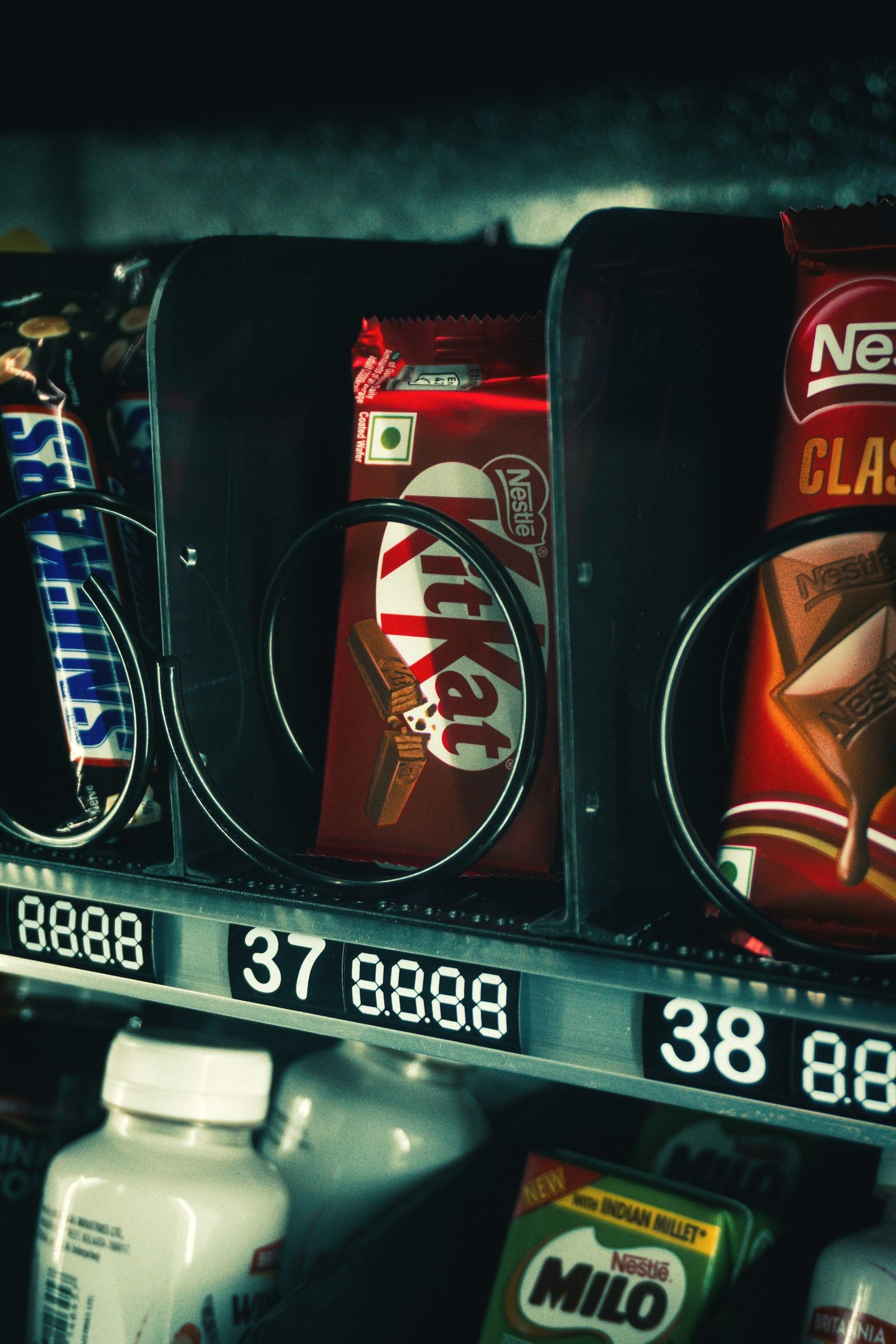 Close-up through vending machine glass of a KitKat bar and other candy in a coiled dispensing rack