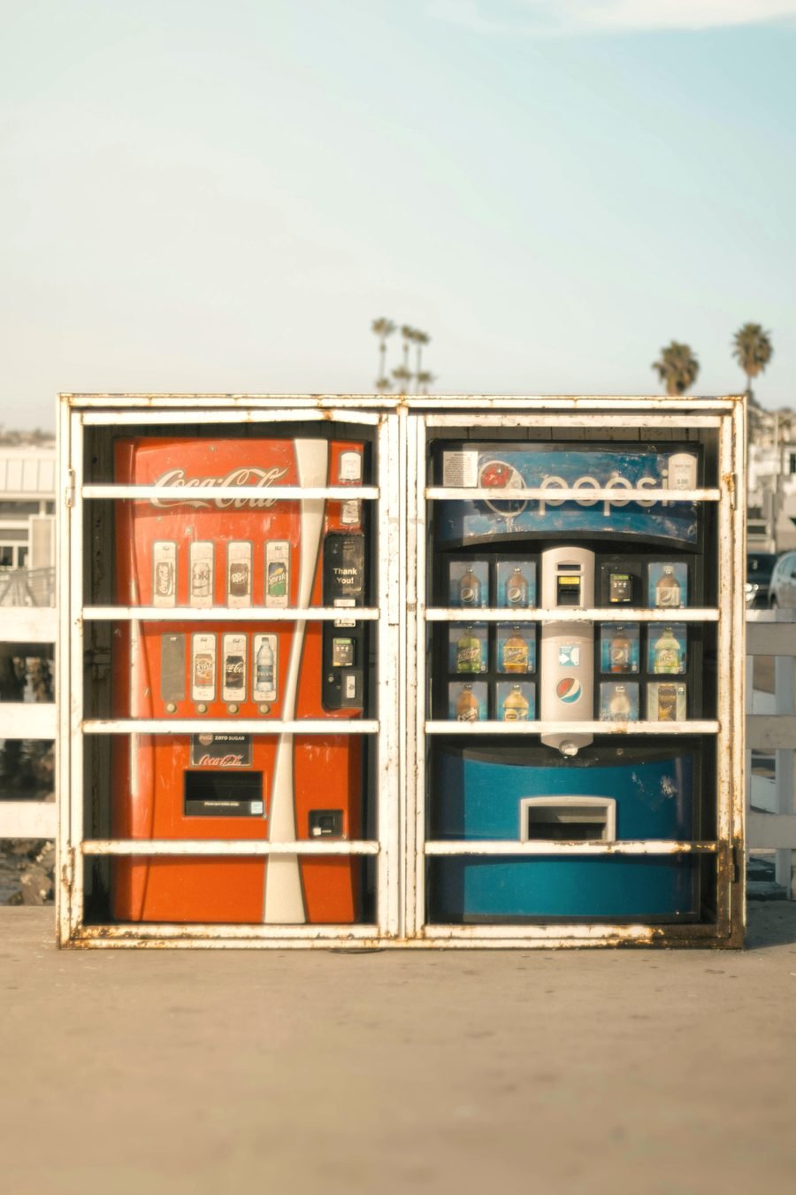 A Coca-Cola machine and a Pepsi machine standing side by side outdoors