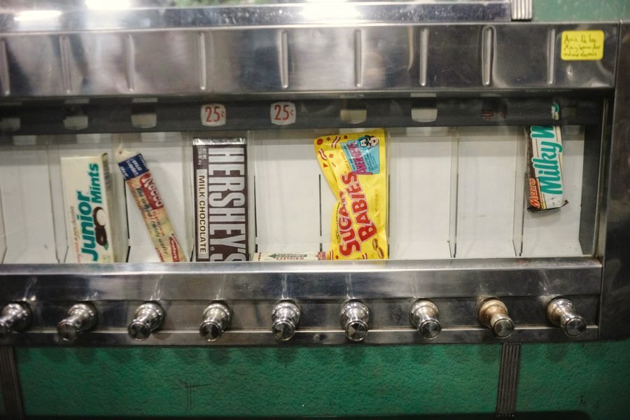 Candy bars including Hershey's, Junior Mints, and Milky Way lined up behind vending machine glass